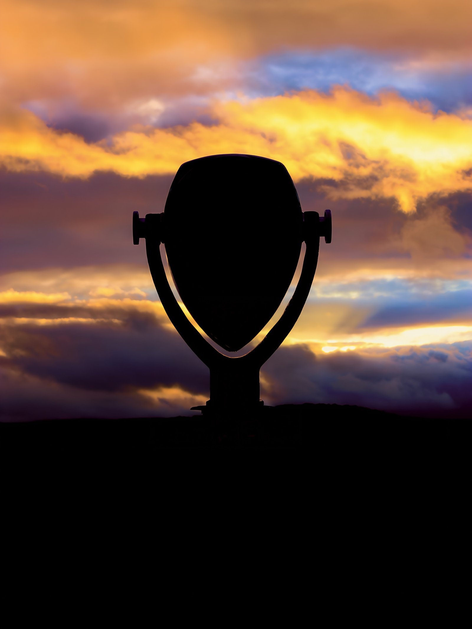 A Tower Optical viewer silhouetted against golden sunset clouds